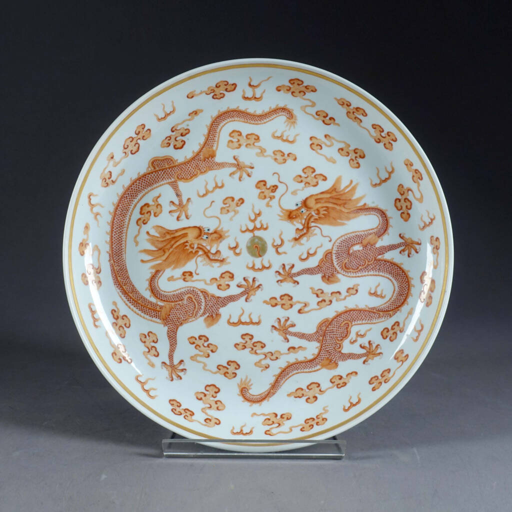 Grand plat rond émaillé rouge de fer et or, à motif de deux dragons s'affrontant autour de la perle précieuse dans des nuages. Porcelaine de Chine. D'époque et à la marque de Guangxu (1875-1908). Coll. Privée.